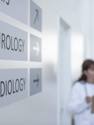 Direction signs on hospital wall with doctors in background