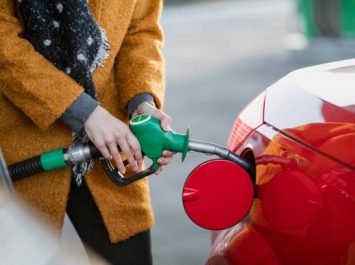 Close up shot of a young businesswoman filling her car with fuel before work.