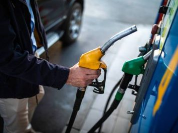 Close up of human hands refilling gas tank at gas station, unrecognizable man