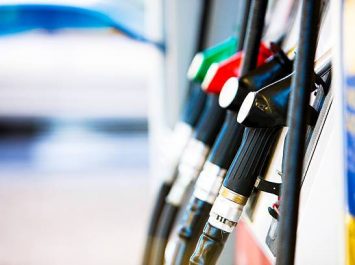 Row of fuel pumps at a gas station, shot with shallow depth of field. Car in the background. Camera: Canon EOS 1Ds Mark III.