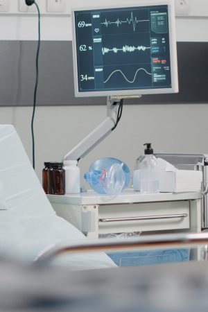Nobody in hospital ward with heart rate monitor and bed for healthcare treatment and recovery. Empty emergency room for intensive care and reanimation with medical equipment and medicine